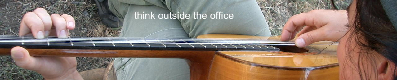 A guitar fretboard held by a woman's hands in an outdoor setting.